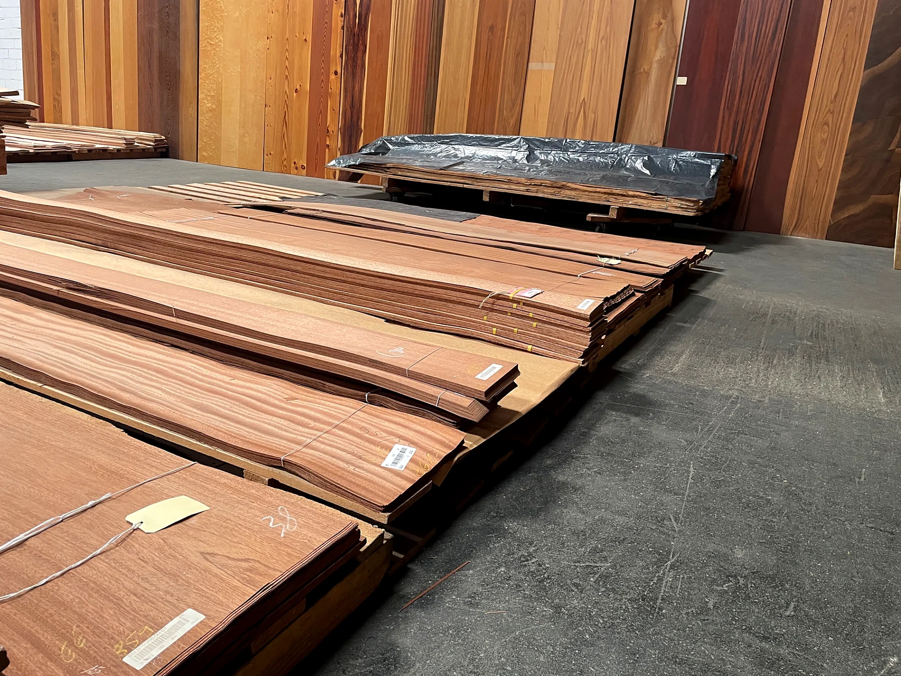 Pakete mit rötlichem Furnier vor der Musterwand aus Furnierbahnen