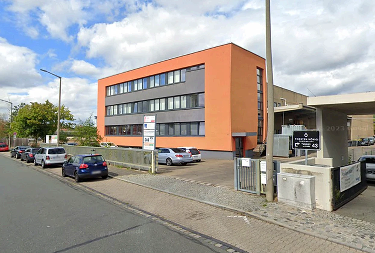 Einfahrt zum Gelände von Studier Furniere neben dem orangefarbenen Bürogebäude